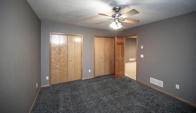 unfurnished bedroom with multiple closets, ceiling fan, carpet, and a textured ceiling