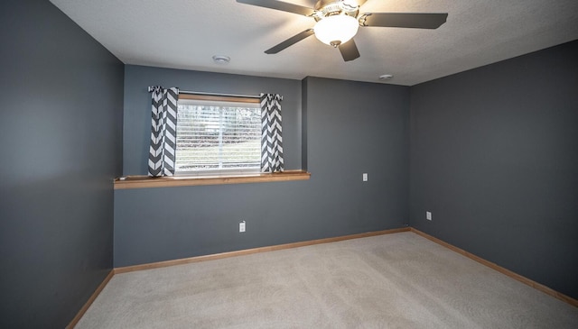 unfurnished room with a textured ceiling, ceiling fan, and light carpet