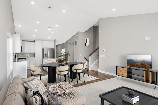 living room featuring high vaulted ceiling and light hardwood / wood-style flooring