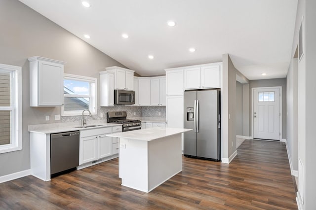 kitchen with stainless steel appliances, sink, a kitchen island, and white cabinets