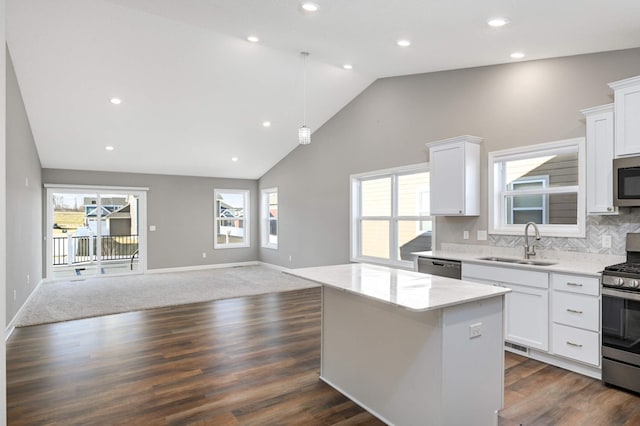 kitchen with sink, stainless steel appliances, a center island, white cabinets, and decorative light fixtures