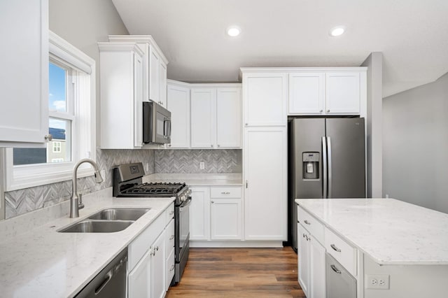 kitchen with white cabinetry, sink, light stone countertops, and appliances with stainless steel finishes