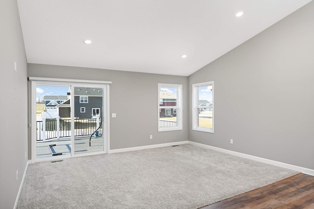 carpeted empty room featuring vaulted ceiling