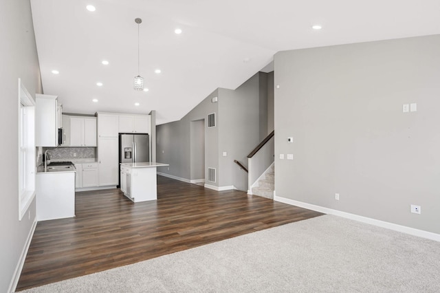 kitchen featuring white cabinetry, tasteful backsplash, a center island, stainless steel fridge, and pendant lighting