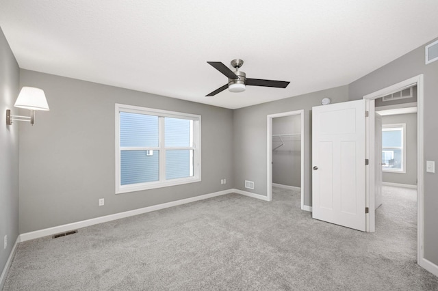 unfurnished bedroom featuring ceiling fan, light colored carpet, a spacious closet, and a closet