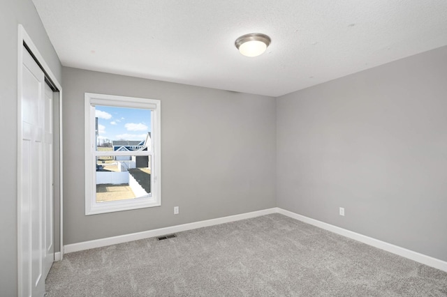 unfurnished room with light carpet and a textured ceiling