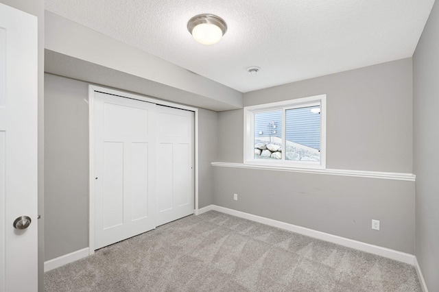 unfurnished bedroom featuring light colored carpet, a closet, and a textured ceiling