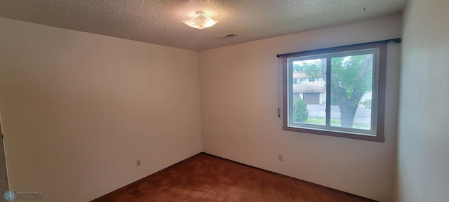 spare room with dark carpet and a textured ceiling