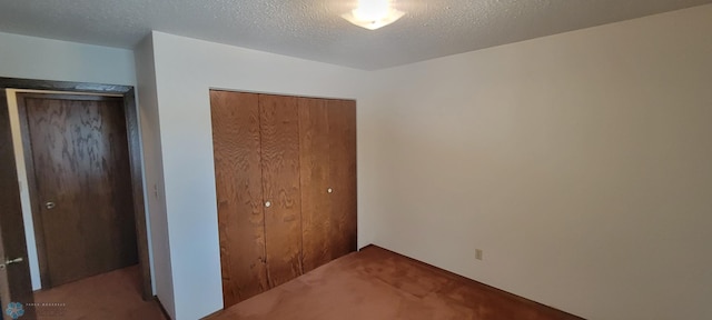 unfurnished bedroom featuring light carpet, a closet, and a textured ceiling