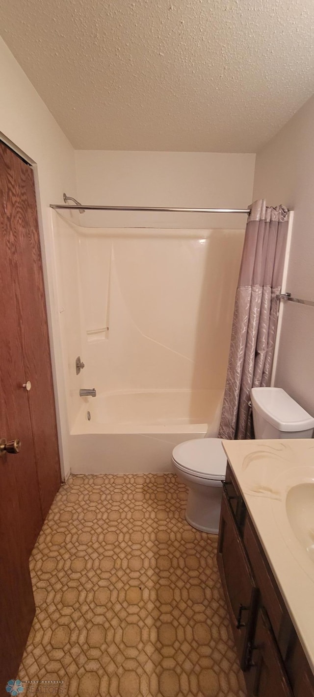 full bathroom with vanity, toilet, a textured ceiling, and shower / tub combo