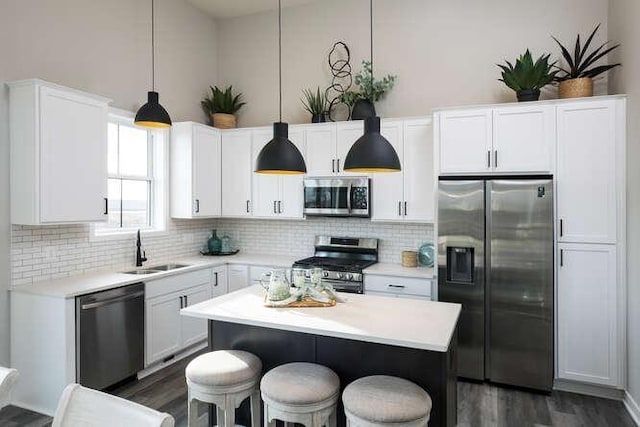 kitchen featuring sink, tasteful backsplash, decorative light fixtures, white cabinetry, and stainless steel appliances