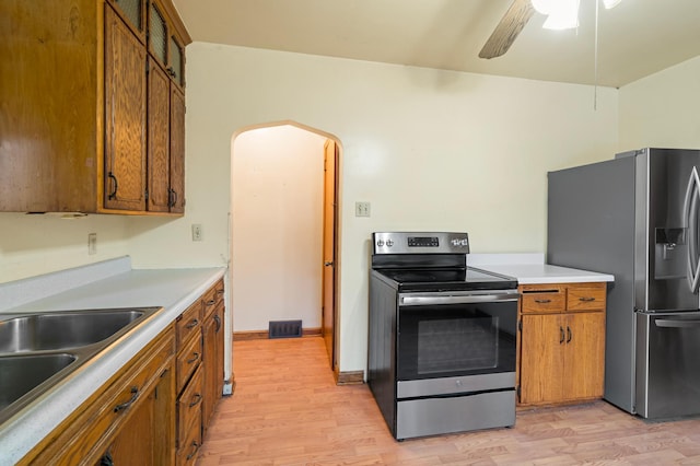 kitchen with ceiling fan, sink, appliances with stainless steel finishes, and light hardwood / wood-style flooring