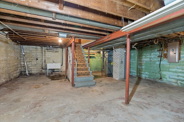 basement with electric panel, heating unit, and sink