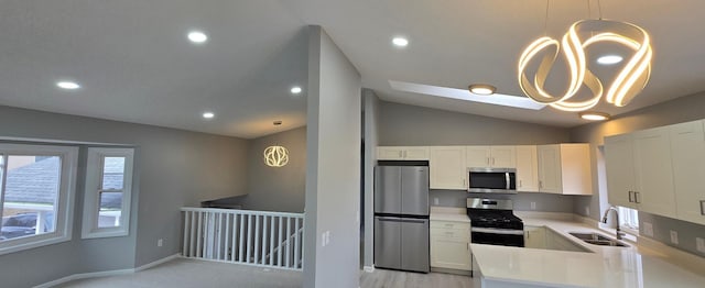 kitchen with light countertops, appliances with stainless steel finishes, white cabinets, vaulted ceiling, and a sink