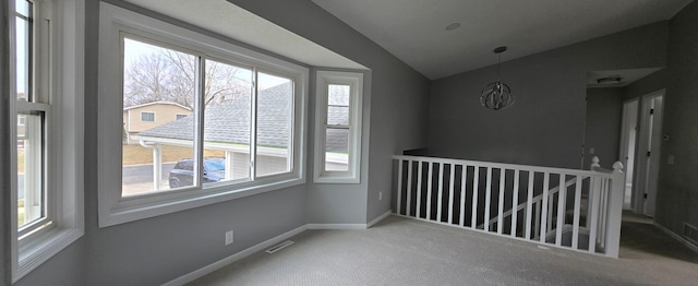 carpeted spare room with lofted ceiling, visible vents, and baseboards