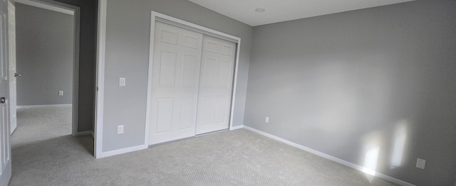 unfurnished bedroom with carpet, a closet, and baseboards