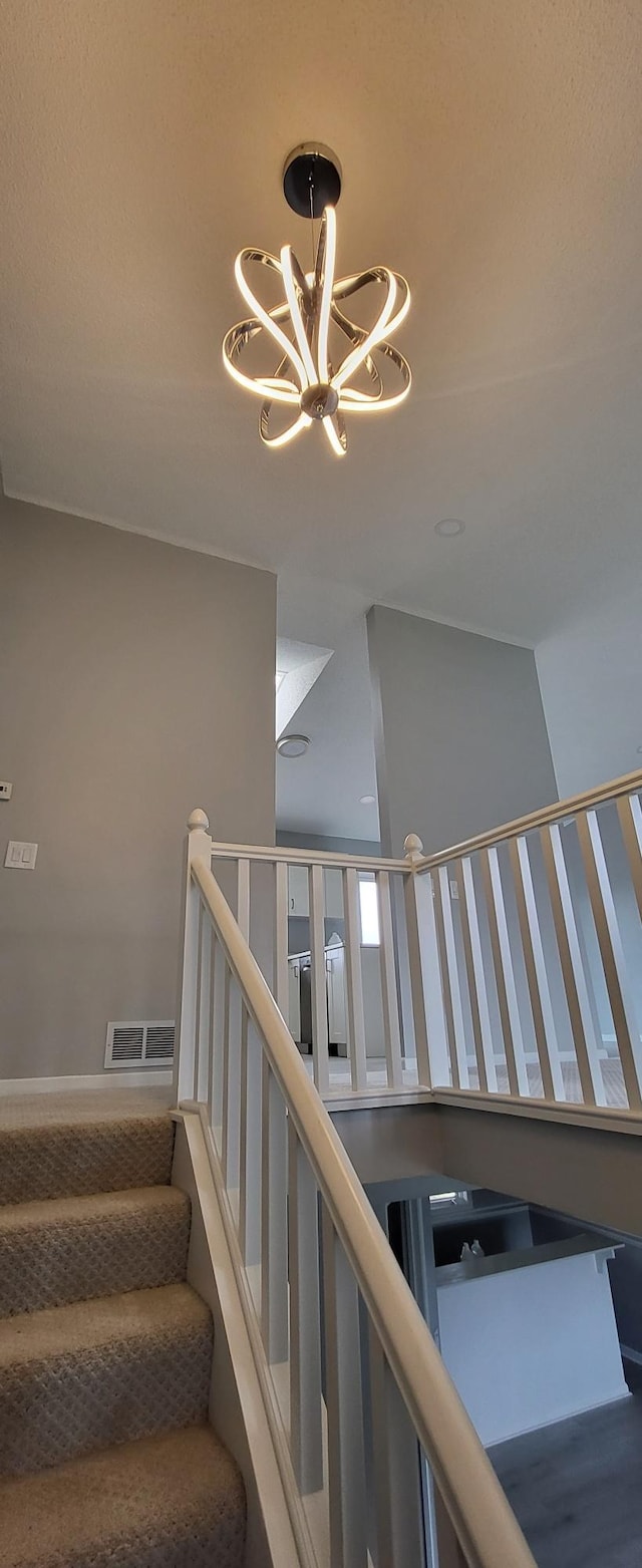 stairway with visible vents and an inviting chandelier