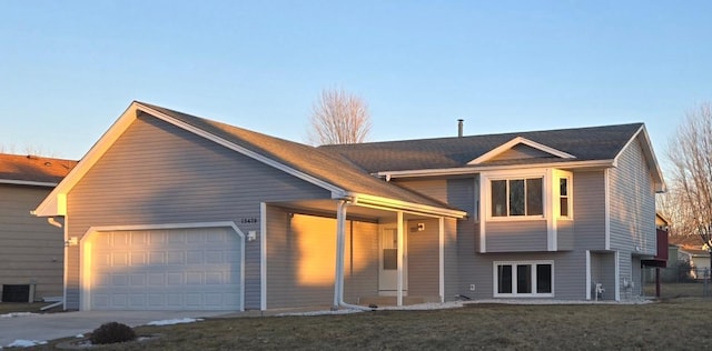 view of front of house featuring a garage, a front yard, and cooling unit