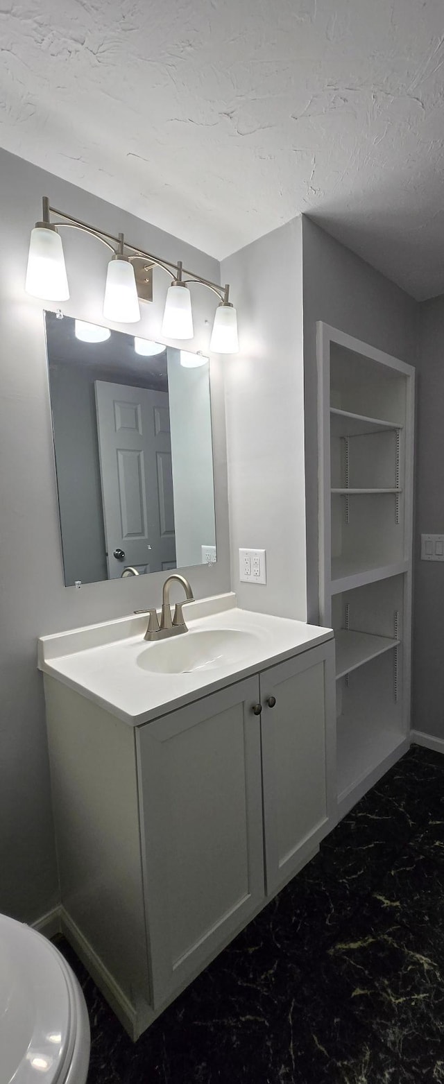 bathroom featuring marble finish floor, vanity, and a textured ceiling