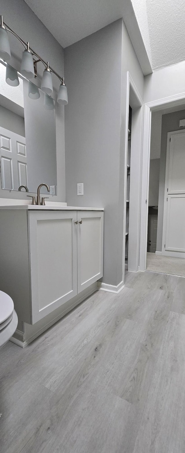 bathroom with baseboards, vanity, toilet, and wood finished floors