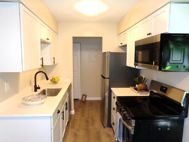 kitchen with white cabinets, stainless steel appliances, hardwood / wood-style flooring, and sink