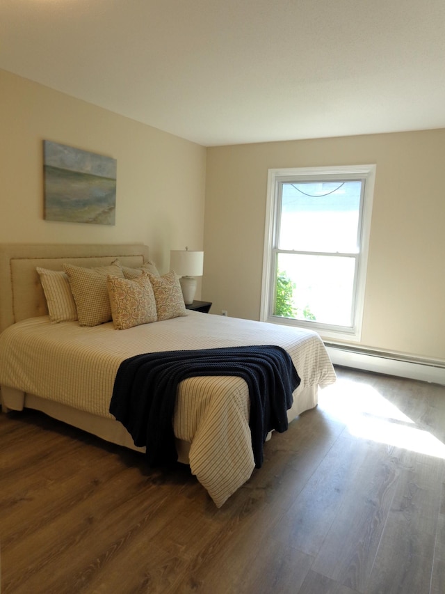 bedroom with dark wood-type flooring and a baseboard heating unit