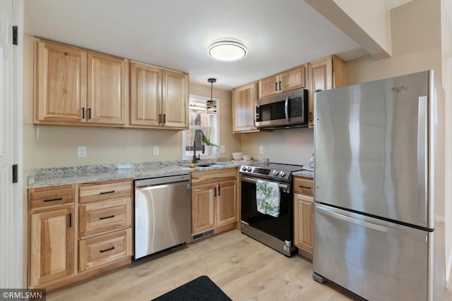 kitchen featuring sink, light stone counters, decorative light fixtures, light hardwood / wood-style flooring, and stainless steel appliances