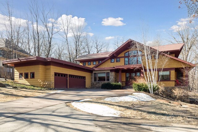 chalet / cabin with driveway, stone siding, and a garage