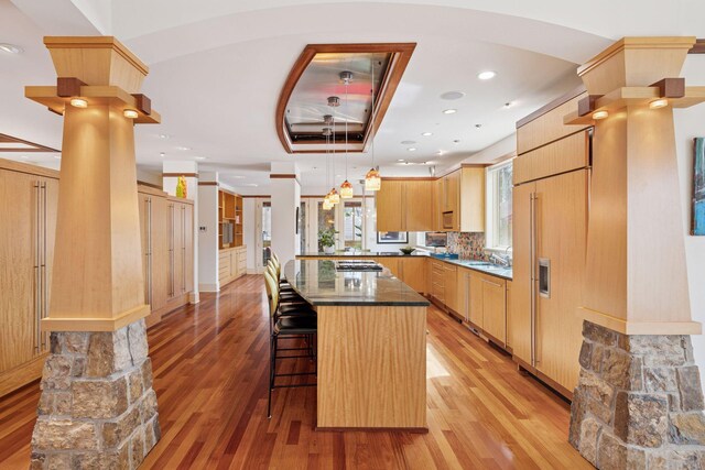 kitchen with a breakfast bar, decorative columns, and light wood finished floors