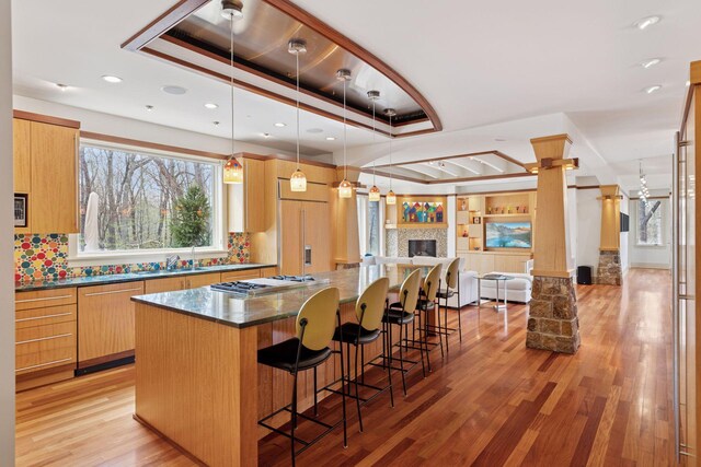 kitchen with light wood-style flooring, a large island, open floor plan, a kitchen bar, and paneled appliances
