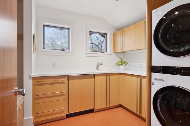 washroom featuring a sink, stacked washer and clothes dryer, and cabinet space