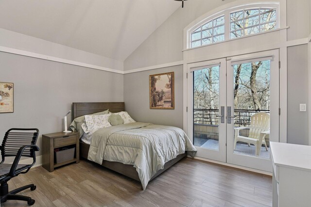 bedroom featuring high vaulted ceiling, french doors, wood finished floors, and access to exterior