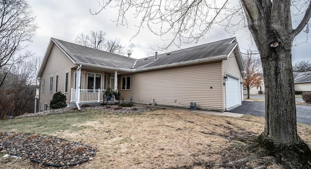 view of home's exterior with a garage, covered porch, and a yard