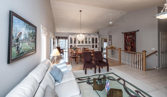 tiled living room featuring ceiling fan with notable chandelier and lofted ceiling