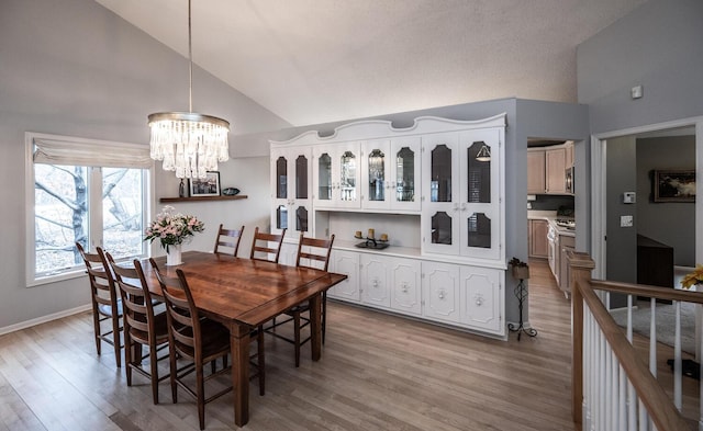 dining area featuring an inviting chandelier, lofted ceiling, and light wood-type flooring