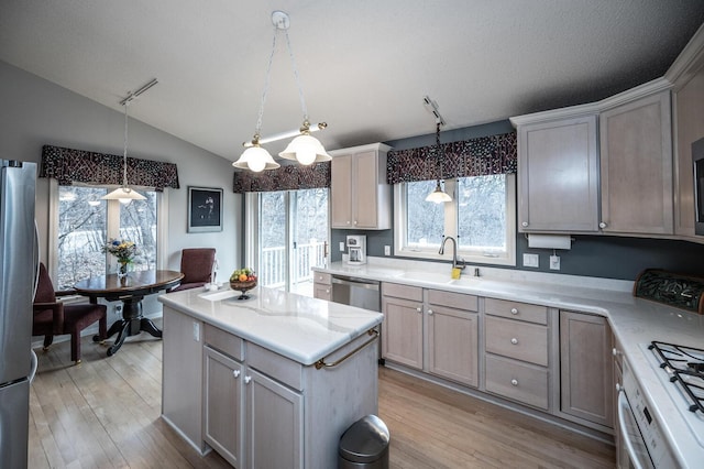 kitchen featuring sink, stainless steel appliances, pendant lighting, vaulted ceiling, and light wood-type flooring