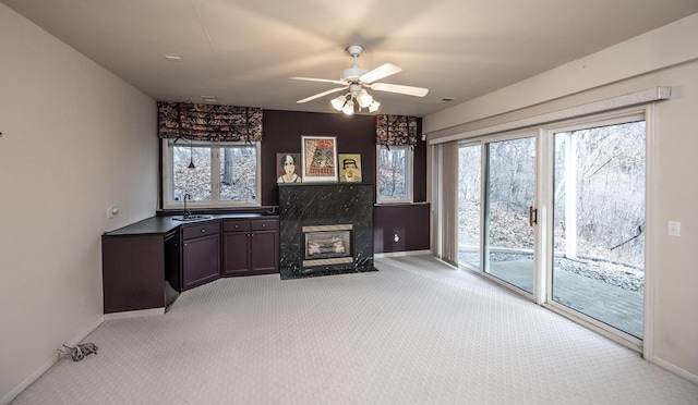 living room featuring a premium fireplace, ceiling fan, sink, and light carpet