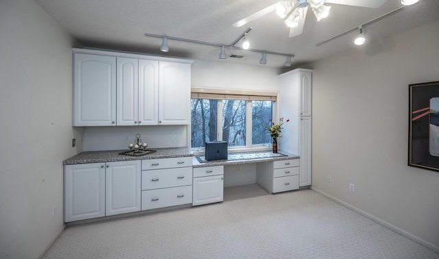 unfurnished office featuring a textured ceiling, ceiling fan, and built in desk