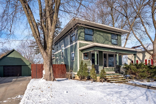 traditional style home featuring a detached garage, fence, a porch, and an outdoor structure