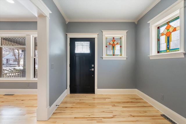 foyer with baseboards, crown molding, visible vents, and light wood finished floors