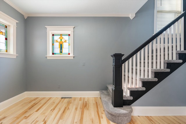 stairway with ornamental molding, wood finished floors, and baseboards