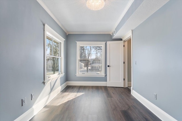 empty room with baseboards, ornamental molding, dark wood finished floors, and a textured ceiling