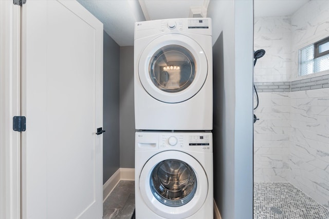 laundry area with baseboards, laundry area, marble finish floor, and stacked washer / drying machine