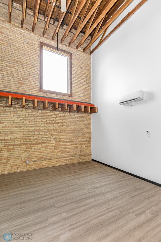 interior space featuring hardwood / wood-style floors, high vaulted ceiling, beam ceiling, and brick wall