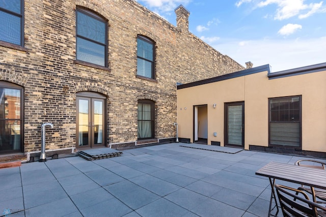 rear view of property with brick siding, a patio, and stucco siding