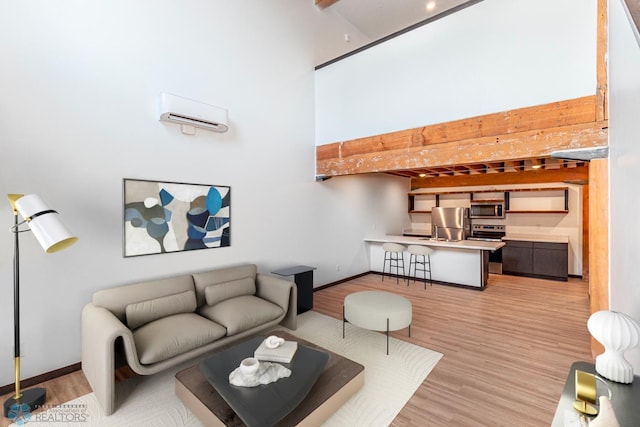 living area with baseboards, a towering ceiling, and light wood-style floors