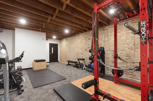 workout area featuring brick wall and carpet floors