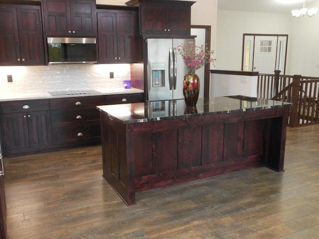 kitchen with a center island, dark stone counters, dark hardwood / wood-style floors, decorative backsplash, and stainless steel appliances