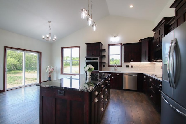 kitchen with decorative backsplash, stainless steel appliances, sink, pendant lighting, and a center island