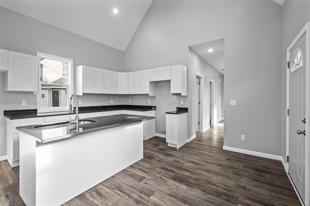 kitchen with white cabinets, a center island with sink, high vaulted ceiling, and sink